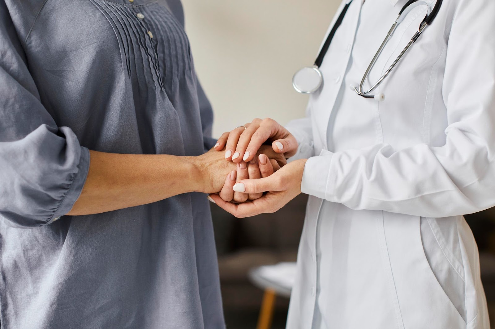 Female doctor holding older patient's hands