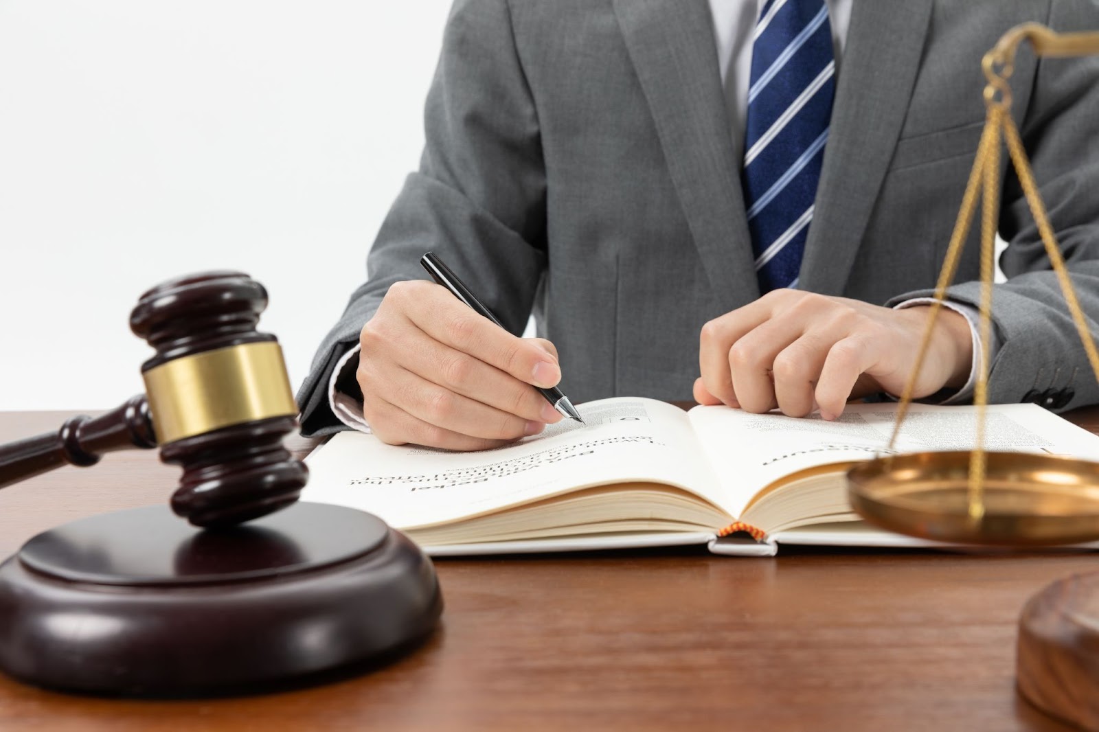 Closeup of a person writing in a book with a gavel on the table