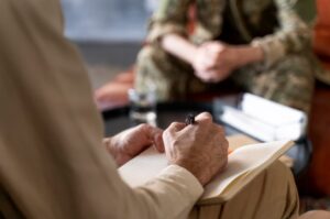 A therapist takes notes during a session with a military veteran