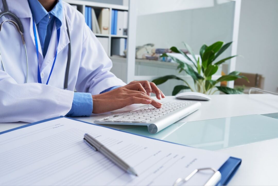 Close up of female doctor typing on keyboard in office