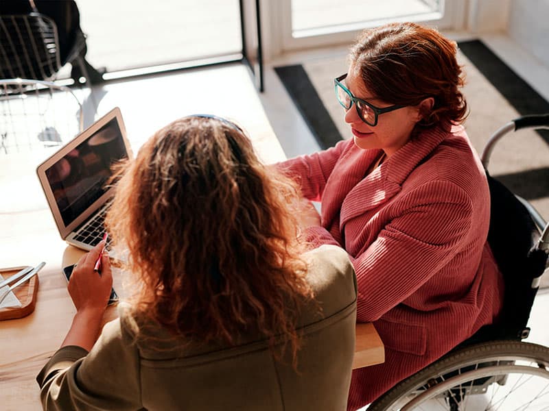 A woman in a wheelchair communicates with another woman