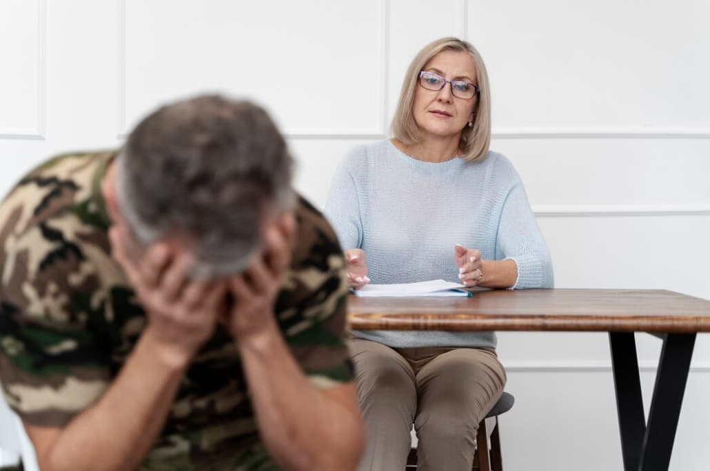 A distressed veteran sits opposite a counselor during a therapy session